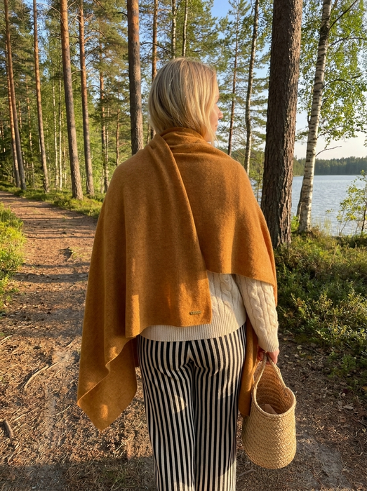 Suuri kashmirhuivi kinuski naisen harteilla metsäpolulla