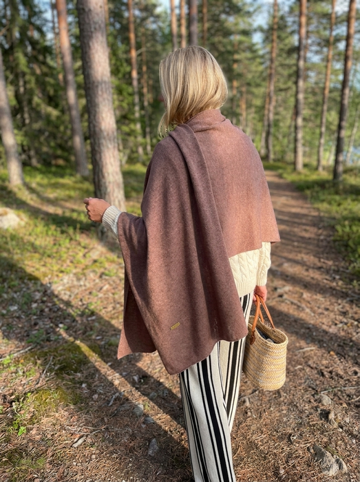 Suuri kashmirhuivi kaakaon ruskea naisen harteilla metsäpolulla