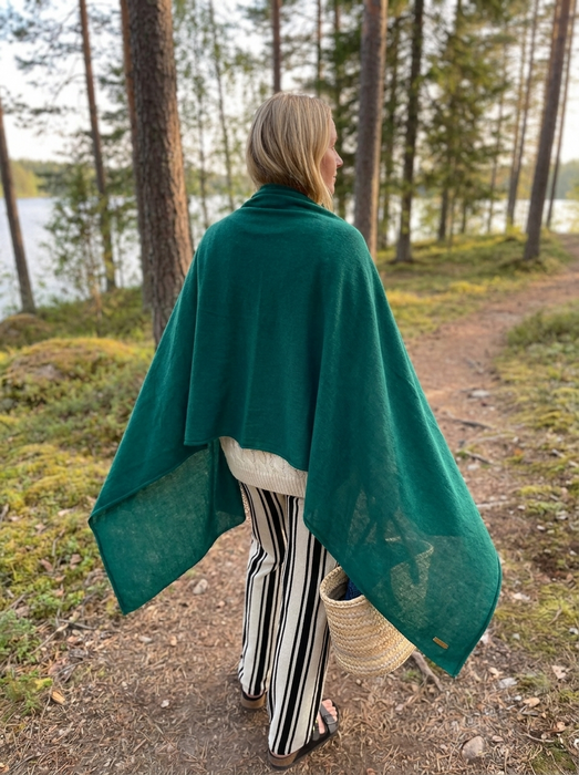Suuri kashmirhuivi metsänvihreä naisen harteilla järven rannalla
